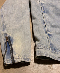 Close-up of light blue denim jeans with a zipper on a beige surface